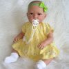 AD8e Levensechte Babypop Kristina softbody bruine ogen in geel gebloemd en speen 52 cm